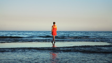 Young women watching the ocean in coast of Tavira, Portugal