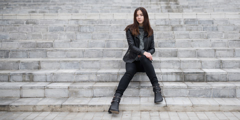 Pretty young woman sitting on the stairs outdoors