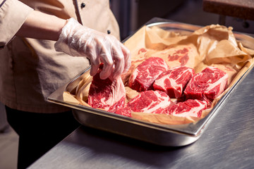 Male chef cooking lamb ribs. Cook preparing delicious meat at restaurant. European cuisine and food. © alfa27