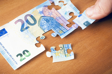 Saving concept: hand putting a piece on a 20 euro puzzle