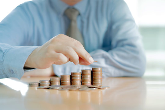 Businessman Sitting at Desk and Stacking Coins