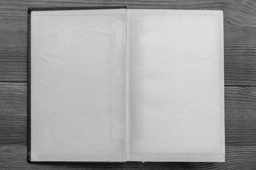 blank pages of an old open book on a wooden table. black and white