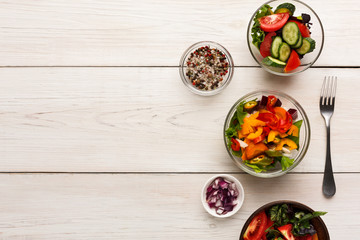 Various salad bowls on white wooden table, top view