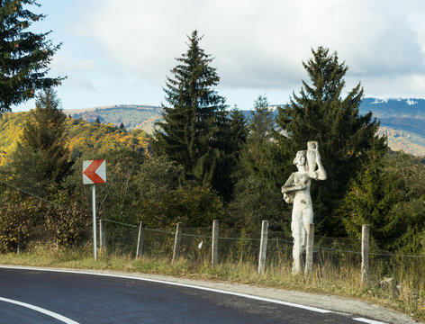 Statue A girl with a pitcher standing by the road passing at the foot of the Carpathian Mountains near the town of Bran in Romania
