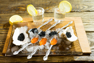 black caviar to oysters, and spoon on the ice, next to two cups of vodka.