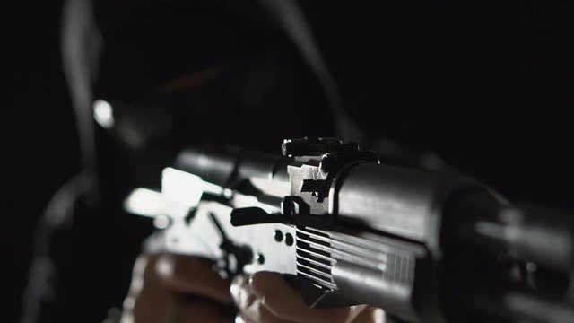 Armed man in black. Bandit with weapons in hand on a black background. The criminal scene. Hands with a gun close-up