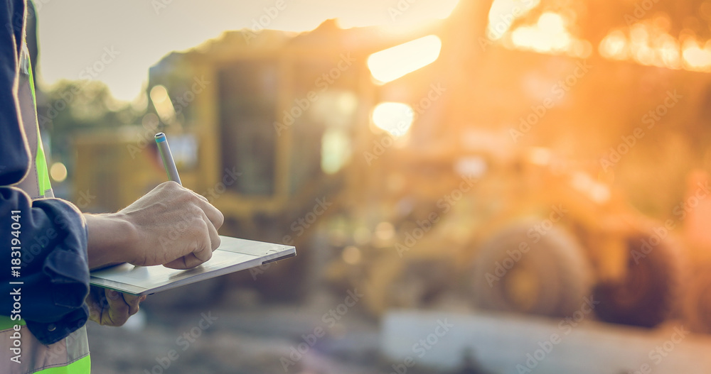 Poster asian engineer with hardhat using tablet pc computer inspecting and working at construction site