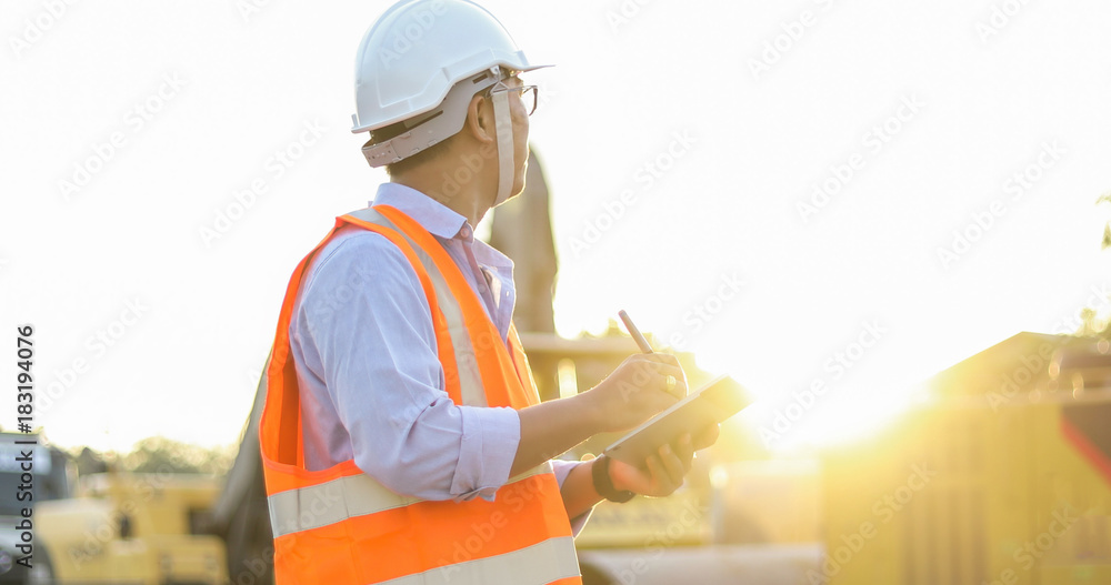 Poster asian engineer with hardhat using tablet pc computer inspecting and working at construction site
