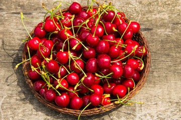 Basket with red sweet cherry fruits on vintage wooden table. Summer fruit season concept