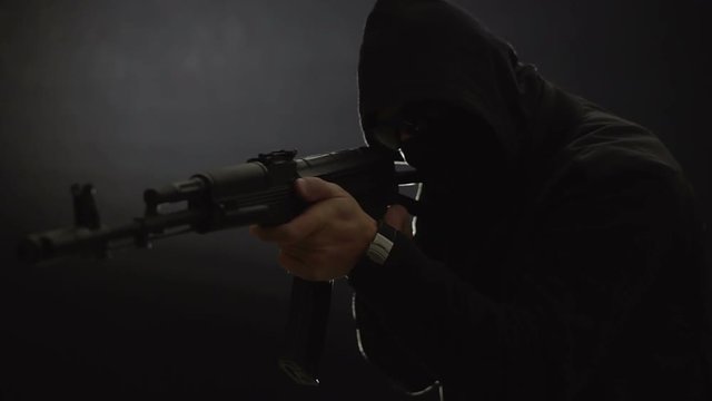 Armed man in black simulates shooting a machine gun. Bandit with weapons in hand on a black background. The criminal scene. Hands with a gun close-up