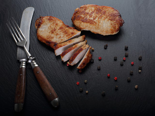 Grilled beef  steaks with fork and knife on slate stone