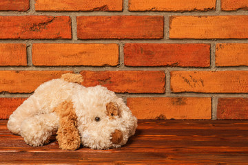 Cute puppy toy on the background of old red brick wall. New Year on the Eastern calendar - Year of the Dog