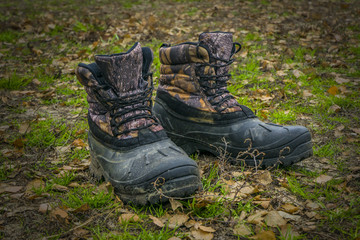 A pair of worn hiking boots on natural background. Dirty boots for hiking, fishing, traveling.