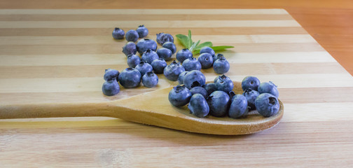 Blueberries on bamboo cutting board and wooden spoon