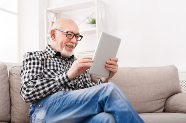 Senior man reading news on digital tablet