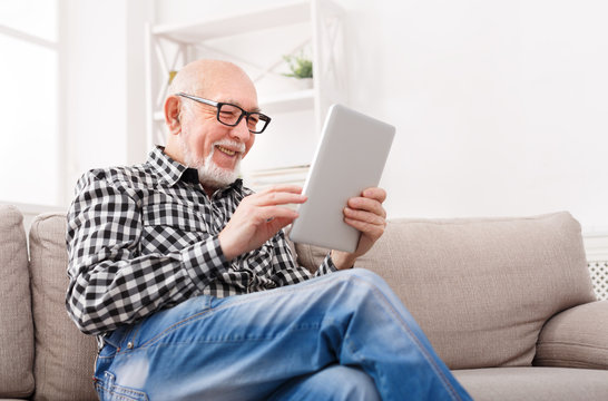 Senior Man Reading News On Digital Tablet