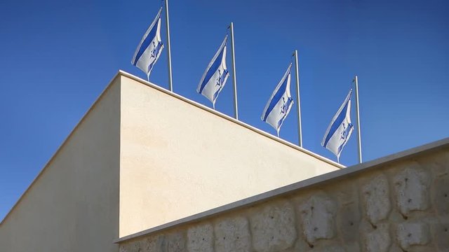 Flags of Israel flapping in wind at top of the building