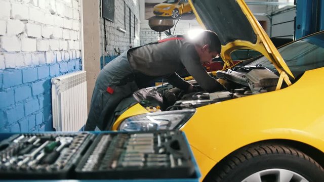Yellow car in garage auto service - open hood - engine repairing