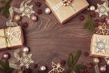 Christmas holiday composition, ornament. Festive creative gold pattern, spruce branches, xmas tree, xmas golden decor holiday ball with gift and ribbon on wooden brown background. Flat lay, top view