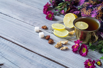 Cup of tea, lemon and flowers on a white wooden table