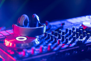 The DJ console cd mp4 deejay mixing desk Ibiza house music party in nightclub with colored disco lights.
