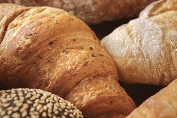 Bread background, closeup of white and black loaves and croissant
