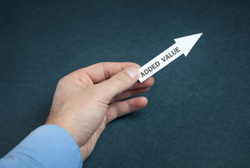 Hand showing paper arrow with a added value word.