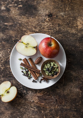 Ingredients for cooking spicy apple tea with spices cinnamon, anise, cardamom, cloves on wooden table, top view. Warming winter drink