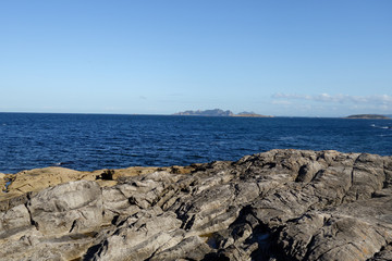Rocky coast by the ocean during sunny day, clear blue sky