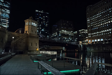 Fototapeta na wymiar Chicago city riverwalk promenade at night with vintage drawbridge and illuminated urban downtown buildings.