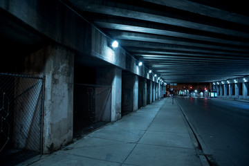 Gritty dark Chicago city street with industrial train bridge viaduct tunnel at night.