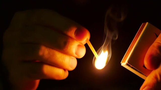 Man lights up a machstick with the matchbox in the darkness. Slow motion. Oxygen and sulfur mixture burns steadily, igniting the matchstick to produce a usable flame. Recorded at 96 fps, Running at 25
