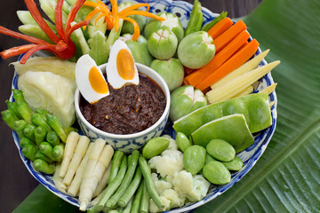 Stir fried shrimp paste and chili (Nam prik pao) eaten with vegetables and salted egg in white bowl on banana leaf Thai food