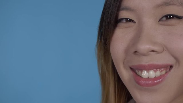 close up portrait part face young asian woman on blue background in studio. attractive millennial girl looking at the camera