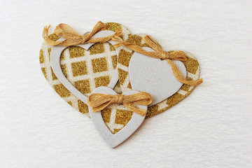 White patterned background with golden hearts. Three gilded hearts in the center of the frame. Copy space for text. Background for Valentine's Day, wedding, postcard