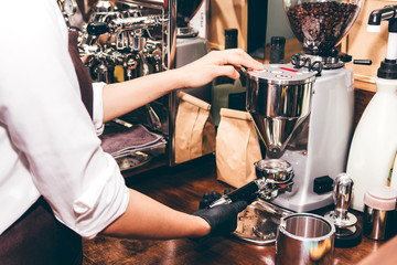 Women Barista using coffee machine for making coffee in the cafe