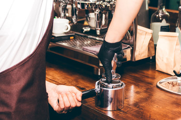 Barista using tamper to makes coffees in coffee bar