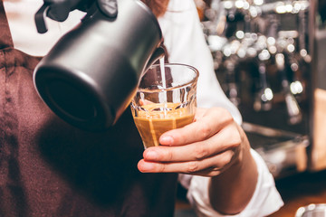 Barista holding milk for make coffee latte art in coffee shop
