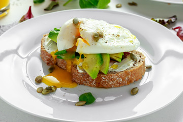 Sandwich, toast with avocado, soft cheese and poached egg on white background