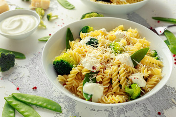Pasta with green vegetables broccoli, Mange tout and creamy sauce in white plate