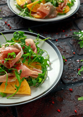 Fresh Tasty Persimmon salad with arugula, parma ham, olive oil and herbs. autumn, winter healthy food