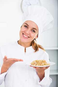 girl in hat and white coat showing porridge