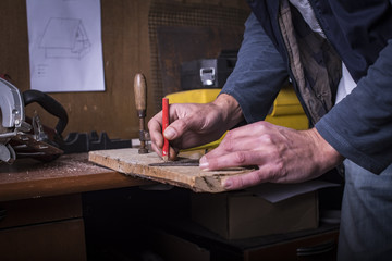 Amateur carpenter marking a line with a protractor on plank