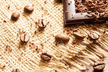 Coffee, chocolate and dried fruits on wood background with linen