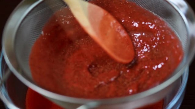 The strawberry puree is poured through a sieve.