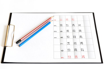 Two pencils on black clipboard with clean sheet of month paper calendar. Isolated. White background
