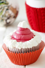 Single Christmas homemade chocolate cupcake with frosting white pink buttercream. White wooden background.