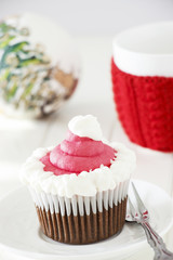 Single Christmas homemade chocolate cupcake with frosting white pink buttercream. White wooden background.