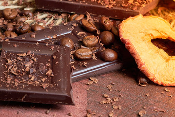 Coffee, chocolate and dried fruits on wood background with linen