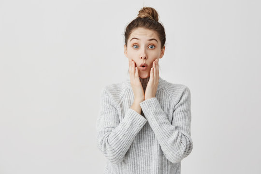 Young Woman Making Surprise With Facial Expressions And Touching Her Cheeks. Girl In Fashion Being Excited To Know Interesting Gossip Goggle At Talker. Human Emotions